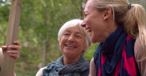 Three generations of woman laughing in a forest, slow motion