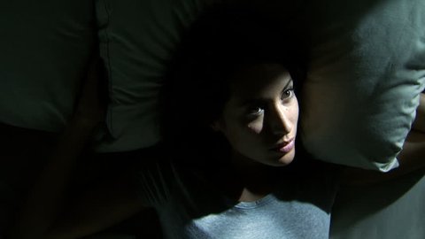 Woman lying awake in bed breathing heavily