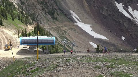 SNOWBIRD, UTAH - AUG 2014: Top of mountain hikers summer ski lift 4k. Exploring natural high Rocky Mountains. Winter and summer resort aerial mountain tram. Tram, chair seats, and family fun.