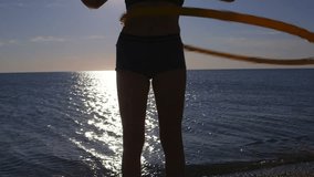 Young girl twirling fitness hula hoop around waist on the beach - Powered by Shutterstock - Get 15% off with code: PIKWIZARD15