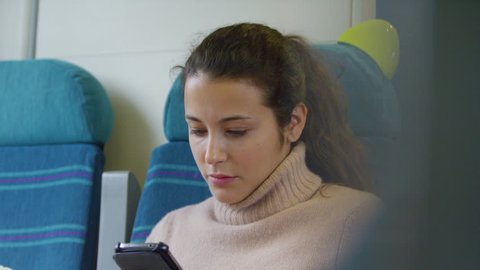 4k Young woman looking at smartphone on train journey. Shot on RED Epic.