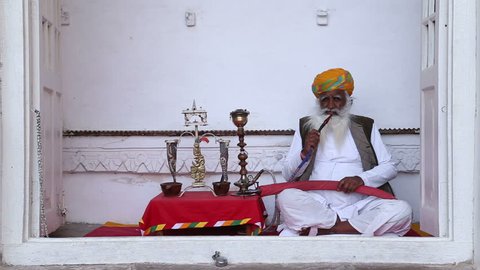 JODHPUR, INDIA - 10 FEBRUARY 2015: Portrait of Indian man in traditional clothing sitting and smoking tobacco.