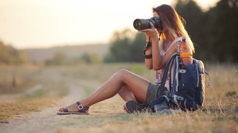 Beautiful young woman journalist in the steppe. Girl with camera on nature. A young woman with a camera on a safari. Travel, tourism, adventure.