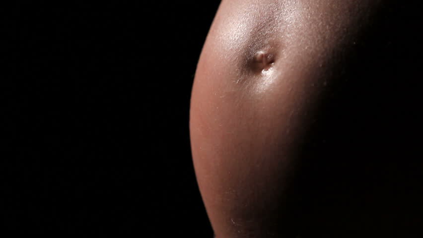 close up of a young mother to be rubbing her pregnant abdomen