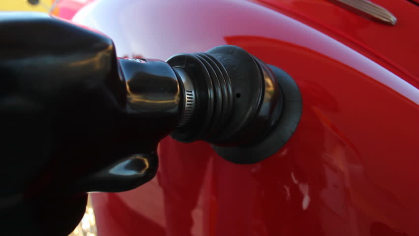 This is a close up shot of a classic car getting filled up with gasoline. 