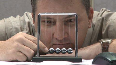 man looking bored playing with kinetic balls