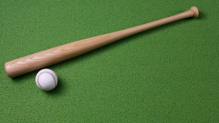 A baseball rolls into the scene an comes to rest next to the bat