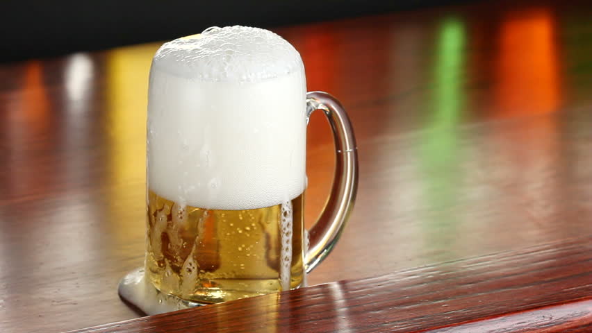 A bottle of beer is poured into a mug in a bar