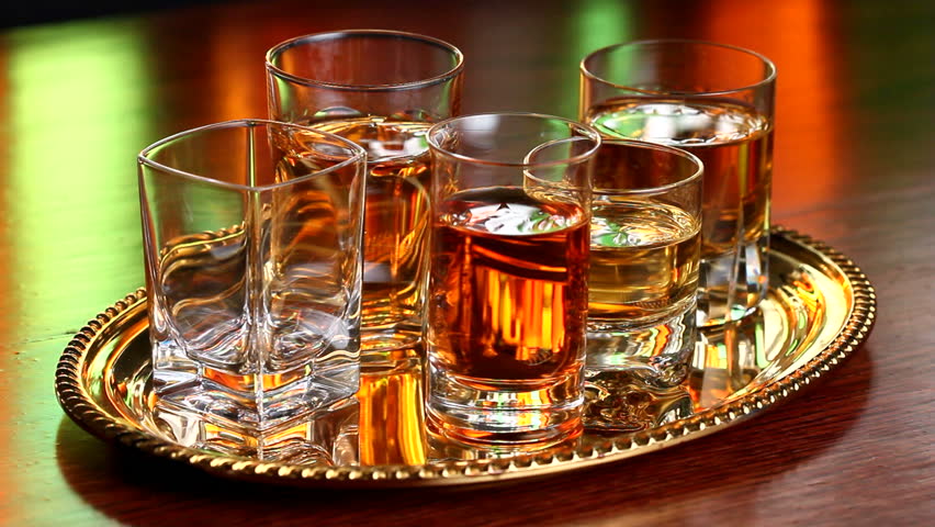 A tray of various kinds of liquors in shot glasses in a bar