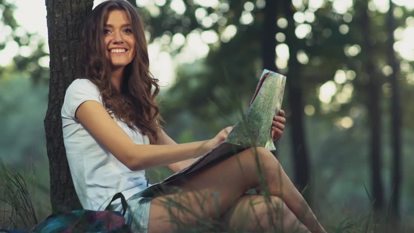 young female with a map smiles,looks to a camera slow motion