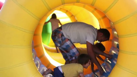 Father and two sons, having fun in a big rolling spherical ring, zorbing