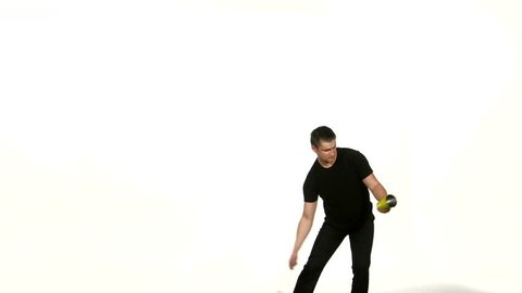 Young bartender does a trick with a shaker and bottle on white background. man in black T-shirt, shakes the shaker, studio