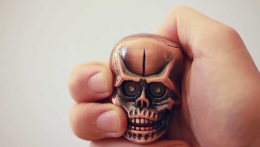 revolving metal lighter in shape of tiny cranium with the glow red eyes in man`s hand