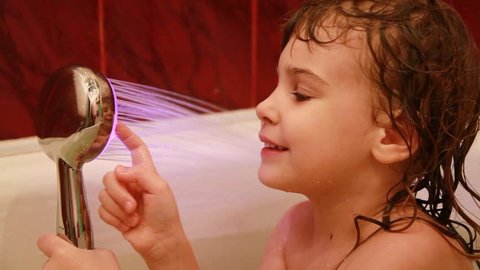 young girl play in the bathroom with led light spray