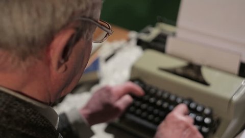 Old man is typing on a typewriter