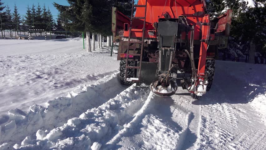 Winter snow cleaning machine is sprinkling salt, sand on a road. UHD 4K steadycam stock footage