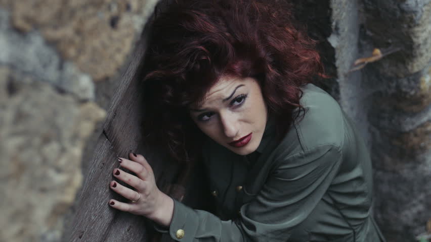frightened young woman takes refuge near an old abandoned house