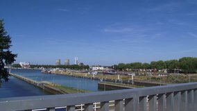 LOCK COMPLEX MAASBRACHT, THE NETHERLANDS - AUGUST 2015: Skyline city of Maasbracht + inland port + pan higher situated Lock complex with video surveillance.  