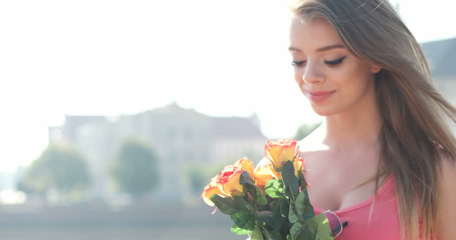 happy brunette teenager  in the city holding a bunch of roses , valentines day gift from her lover 
