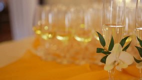Decorated champagne flutes on table during wedding. Footage of champagne flutes decorated with flower on table. Panning shot of alcohol glasses during wedding celebration.
