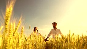 Happy Couple having date outdoors on the wheat field. Healthy family running through the golden field. Boy and girl smiling and having fun together. Slow motion 240 fps. Slowmo 1080 HD video footage