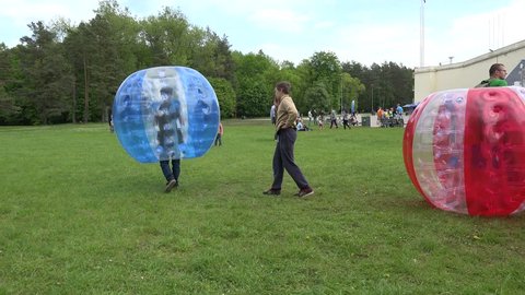 VILNIUS, LITHUANIA - MAY 23: boy climb into large inflated zorb bubble on meadow on May 23, 2015 in Vilnius, Lithuania. 4K UHD video clip. Children freetime outdoor.