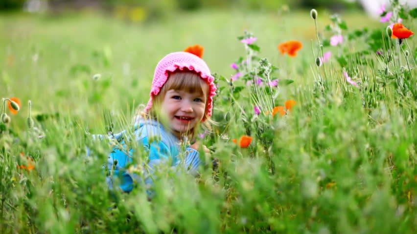 Beautiful child in flowery meadow. Girl laughs