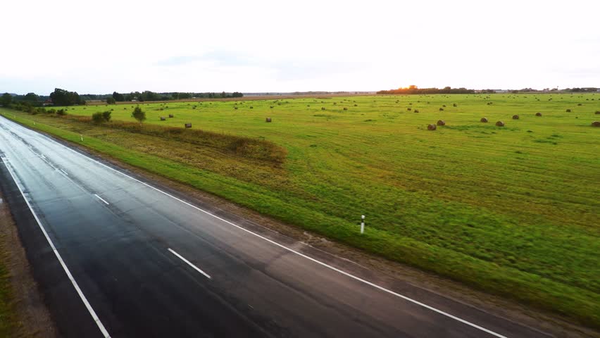 Close shot of blac car on wet road. Aerial footage. Sunset