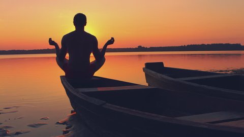 Man doing yoga at sunset