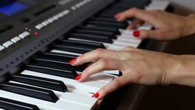 Woman playing a synthesizer - close-up video of a woman hands with red nails manicure