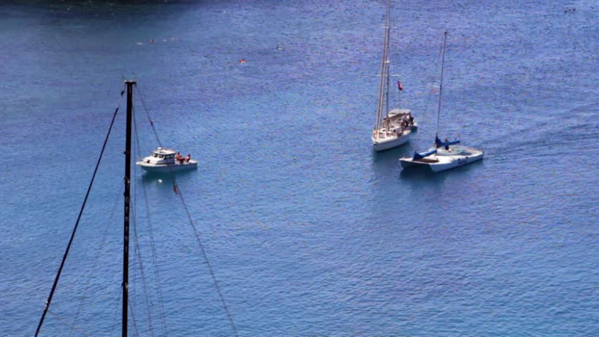 Sailboats sit in a bay off of a tropical island