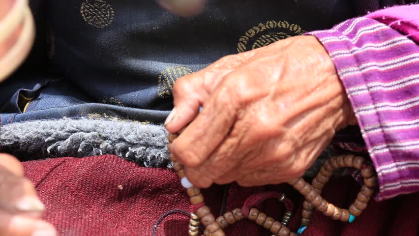 Old Tibetan woman holding buddhist prayer wheel in Lamayuru Gompa, , Ladakh, India. Hand and prayer wheel, close up