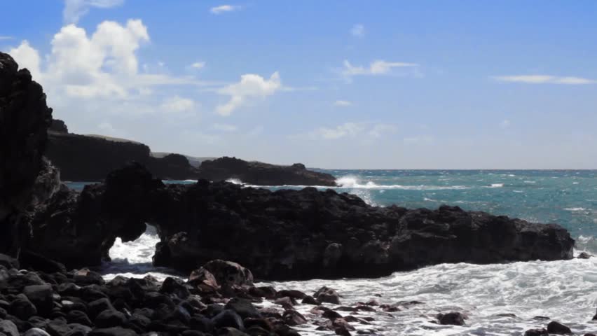 Waves crash through a sea arch on Maui, Hawaii