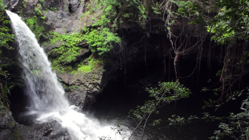 A beautiful jungle waterfall dropping into a big cavern