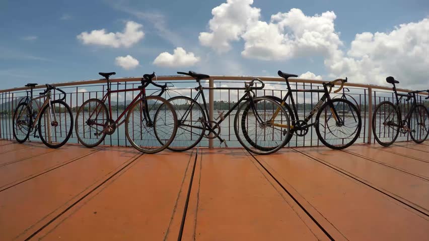 SAN PABLO CITY, LAGUNA, PHILIPPINES - SEPTEMBER 8, 2015: Bicycles leaning line up at lake railings, the leisure equipment of contemporary active people. Tracking shot