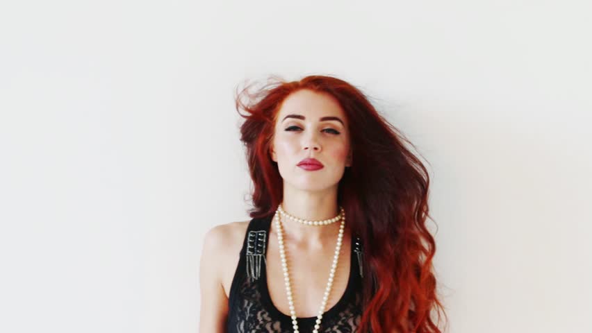 Red hair beautiful woman in beads poses in white studio