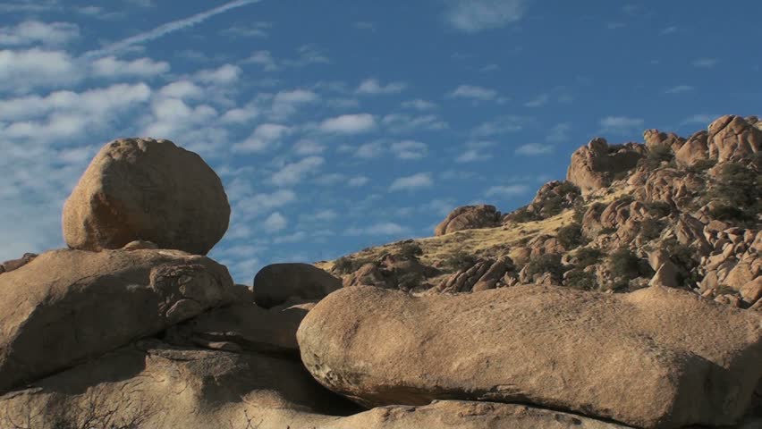 Time Lapse, Small puffs of clouds roll across lumpy, textured, boulder landscape in American southwest. 