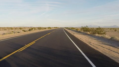 Point of view vehicle driving shot of California Highway 62 through the Mojave desert. Viewpoint of driver over smooth blacktop asphalt on a stretch of desert highway.