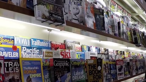 Coquitlam, BC, Canada - October 26, 2014 : Close up hand choosing magazine at London drugs store with wide angle camera shot