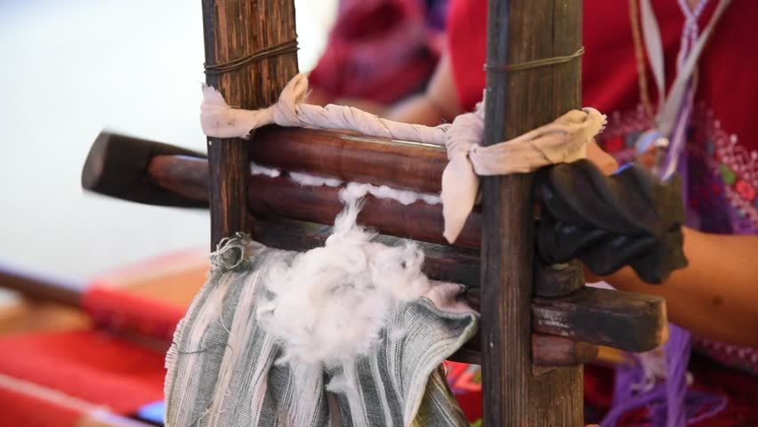Woman spinning wooden wheel prepare cotton fibers in to the basket.