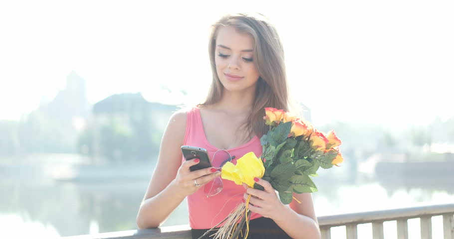 woman sniffing flowers while speaking over the phone, valentines day concept