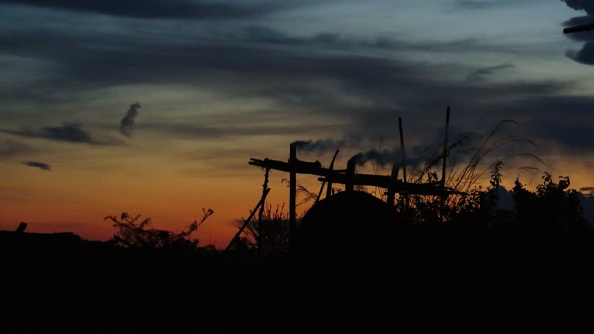 Smoke from smokestack of charcoal kiln over sunset sky,Thailand.