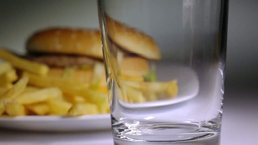 Cola being poured in glass, hamburger and potato chips on background,  slow motion, fast food, junk food concept. Royalty-Free Stock Footage #11605790