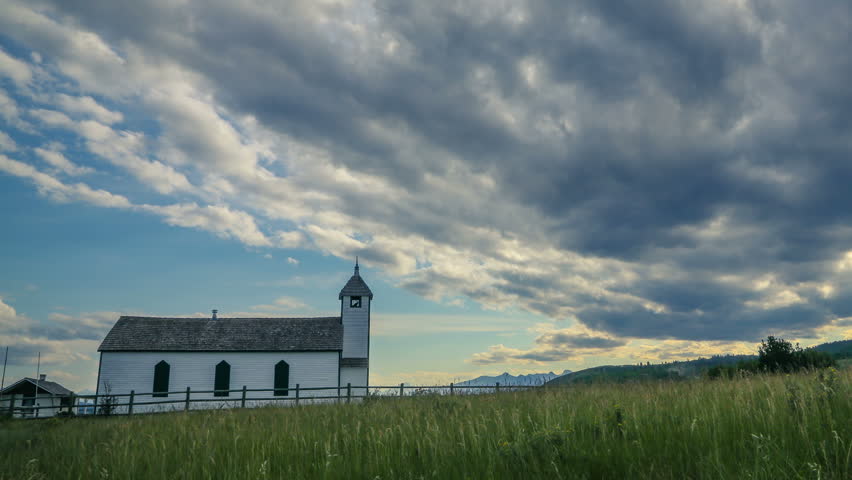 Zoom out time lapse of a small country church under cloudy sky in Alberta, Canada