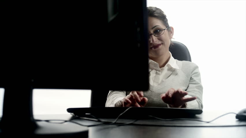 An Hispanic woman at a desktop computer. 