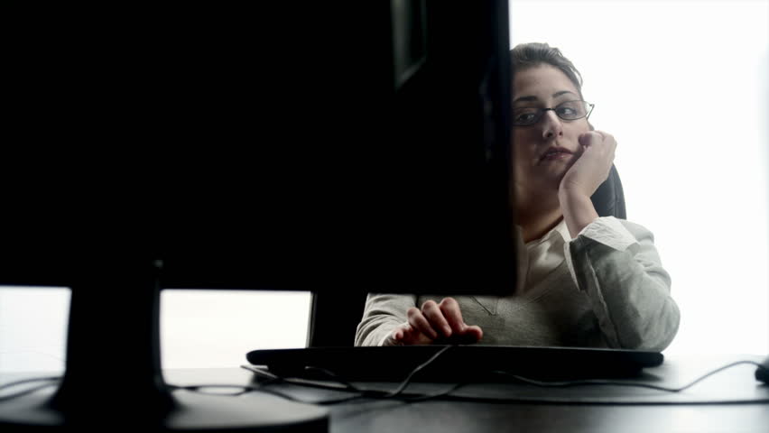 An Hispanic woman falling asleep at a desktop computer 