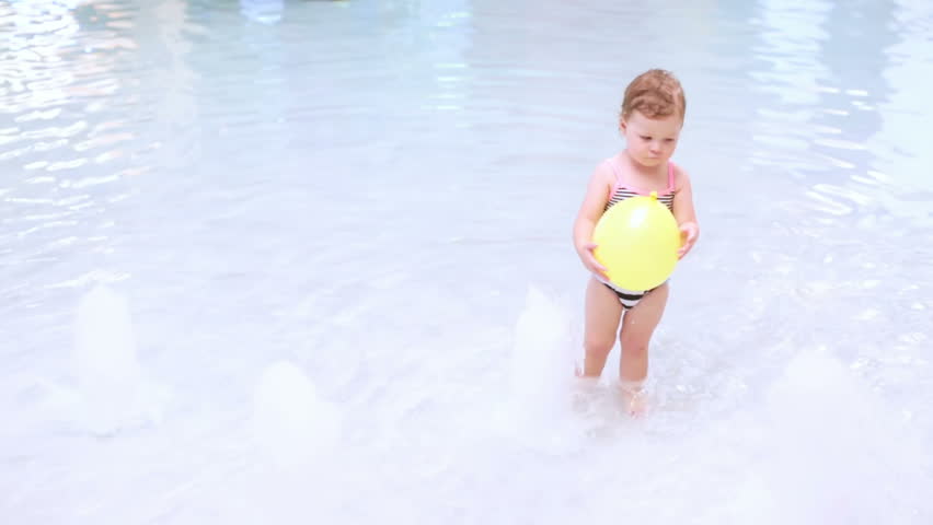 Toddler girl splashing in indoor pool.