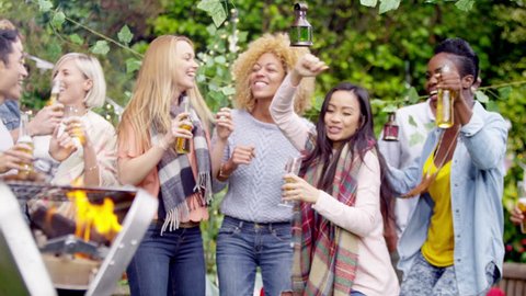 4K Happy mixed ethnicity group of friends dancing & drinking beer at bbq. Shot on RED Epic.