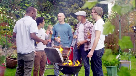 4K Happy mixed ethnicity group of male friends chatting & drinking beer at bbq. Shot on RED Epic.