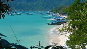 Video 1080p - Dozens of tour boats line the sandy beach and crowd the waters of a beautiful tropical bay in Southern Thailand.